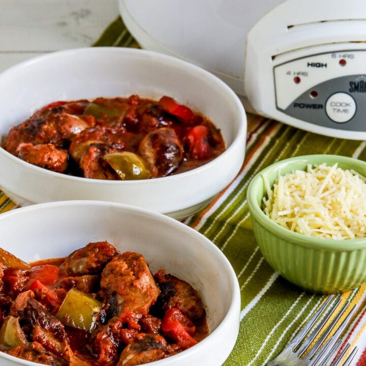 Slow Cooker Sausage and Peppers shown in two bowls with Parmesan and slow cooker in back.