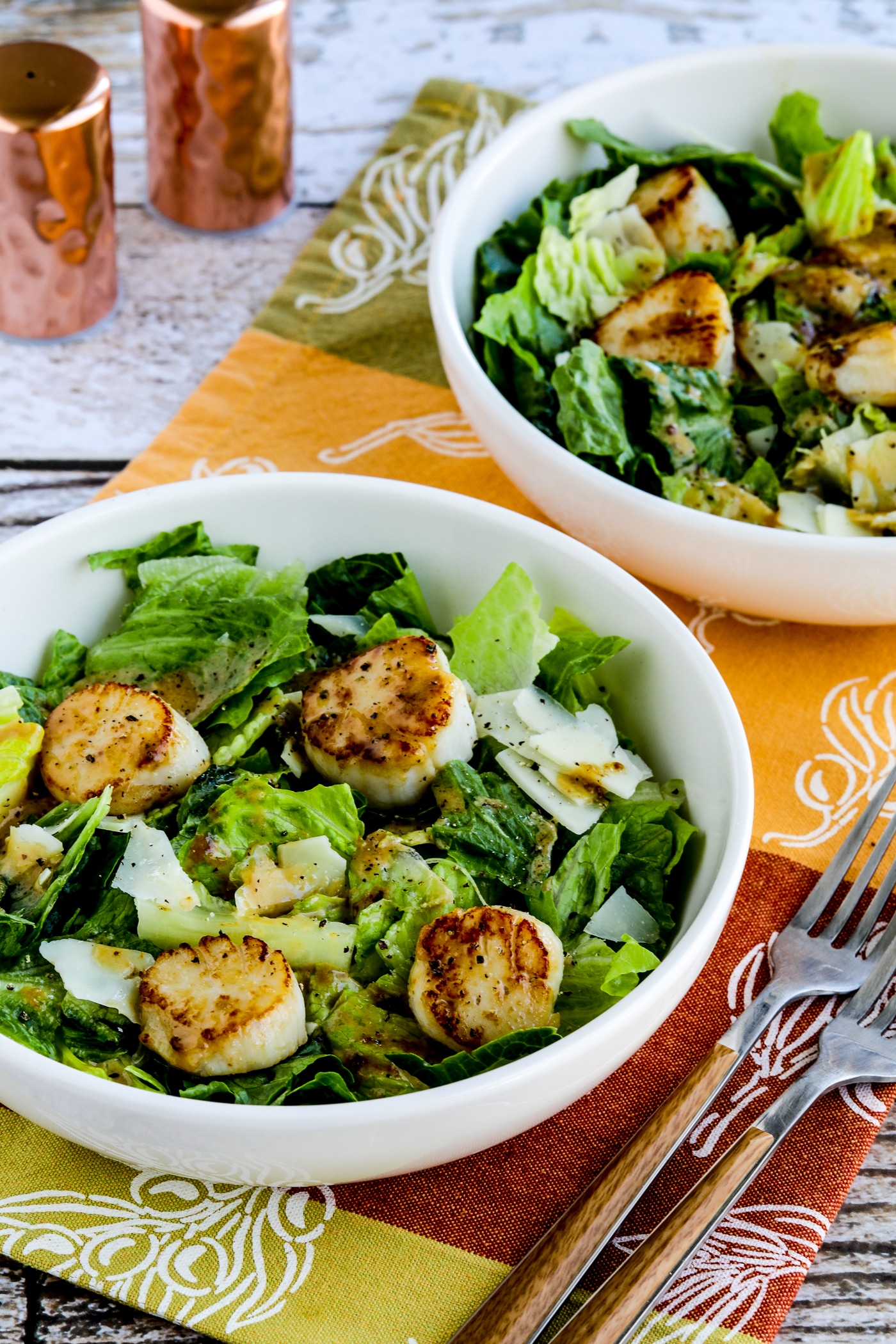 Close-up of a warm Caesar scallop salad shown in two serving bowls