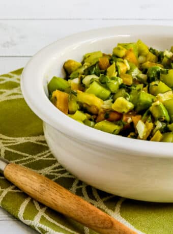 Square image for Green Tomato Salad with Avocado shown in serving bowl on green-white napkin.