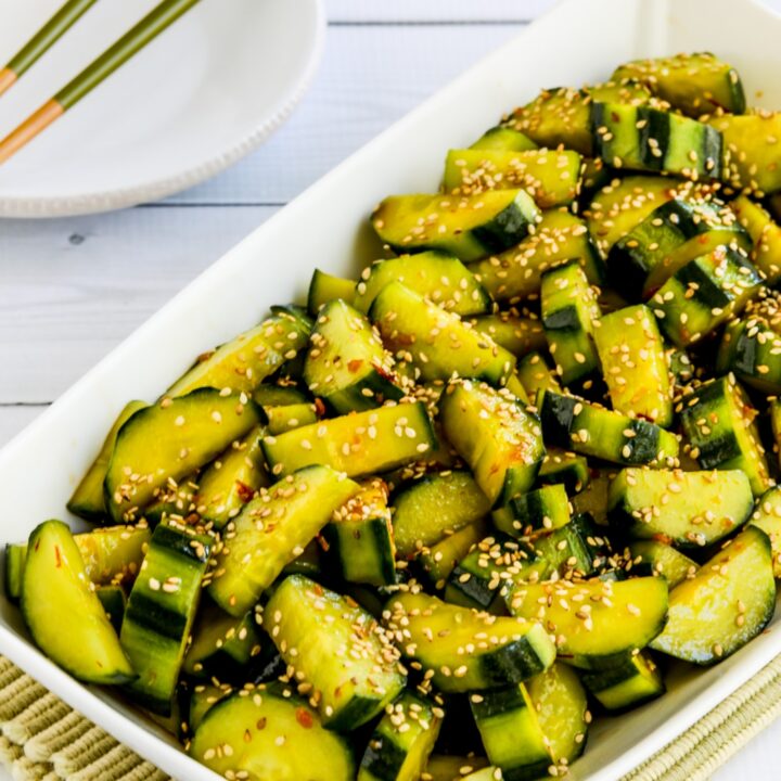 close-up shot of Spicy cucumber salad in serving dish with plate and chopsticks in background