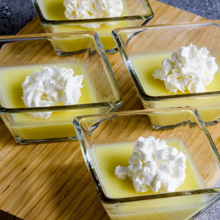 Sugar-Free Jelled Ricotta Pudding shown in four serving dishes with whipped cream on top.