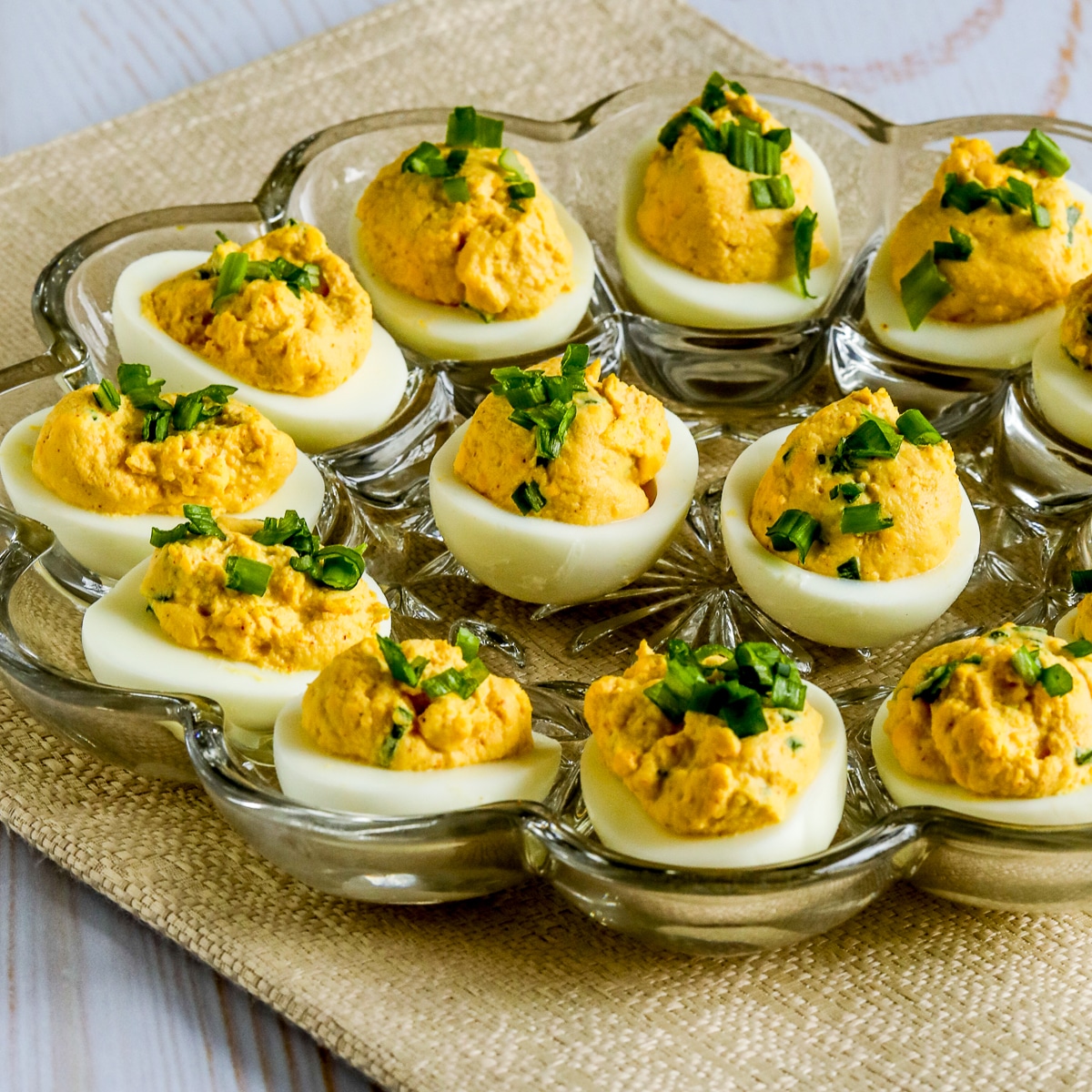 Spicy Deviled Eggs with finely chopped green onion garnish, shown in egg-serving dish.