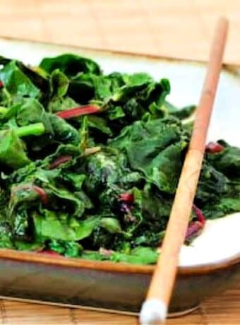 Square image of stir-fried radish greens on serving plate with chopsticks.