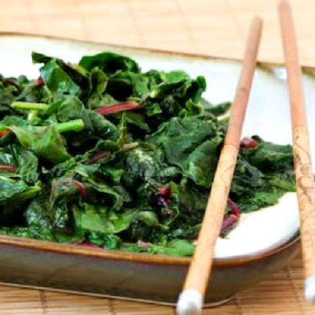 Stir-Fried Radish Greens shown on serving plate with chopsticks
