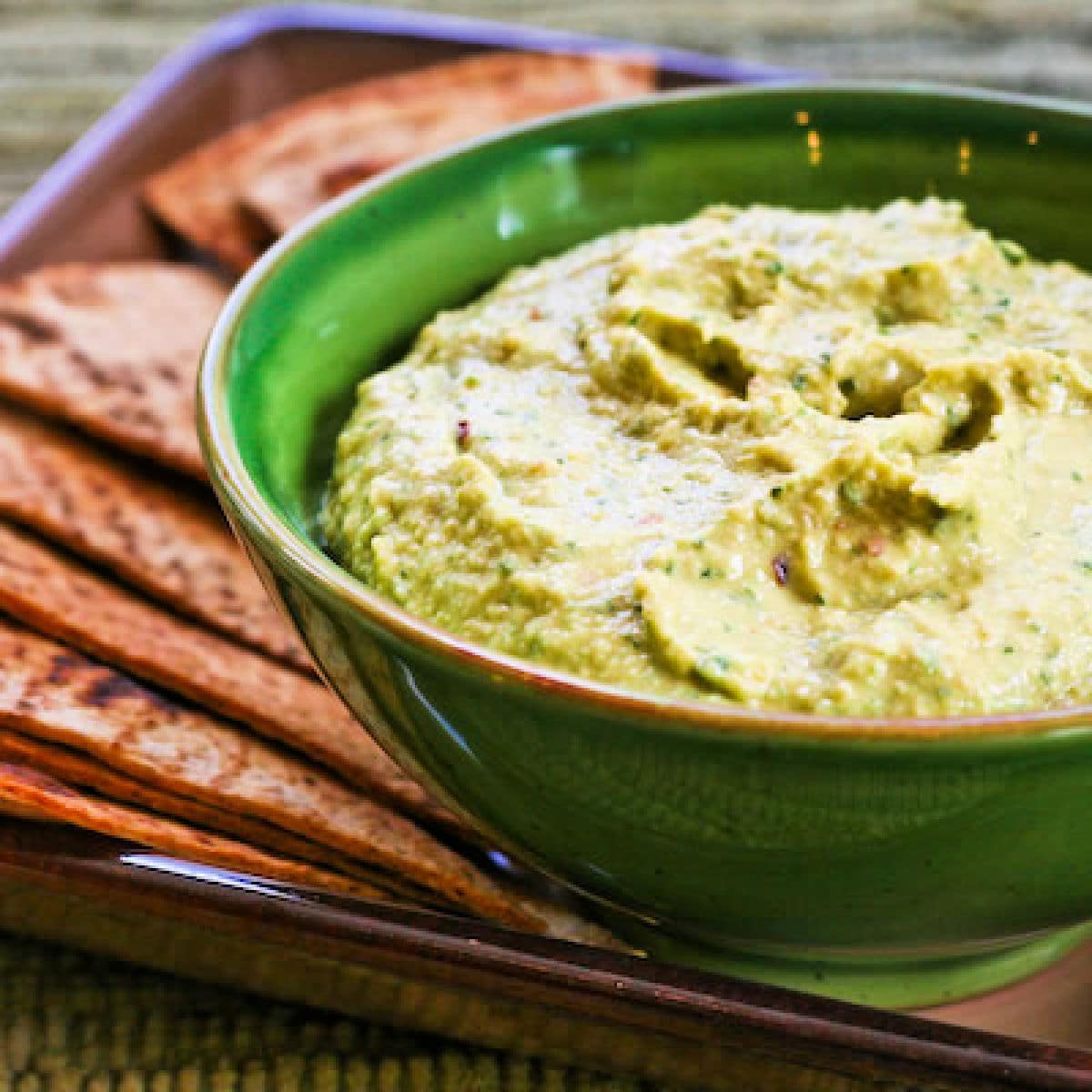 Parsley Hummus shown in serving bowl with low-carb pita bread.