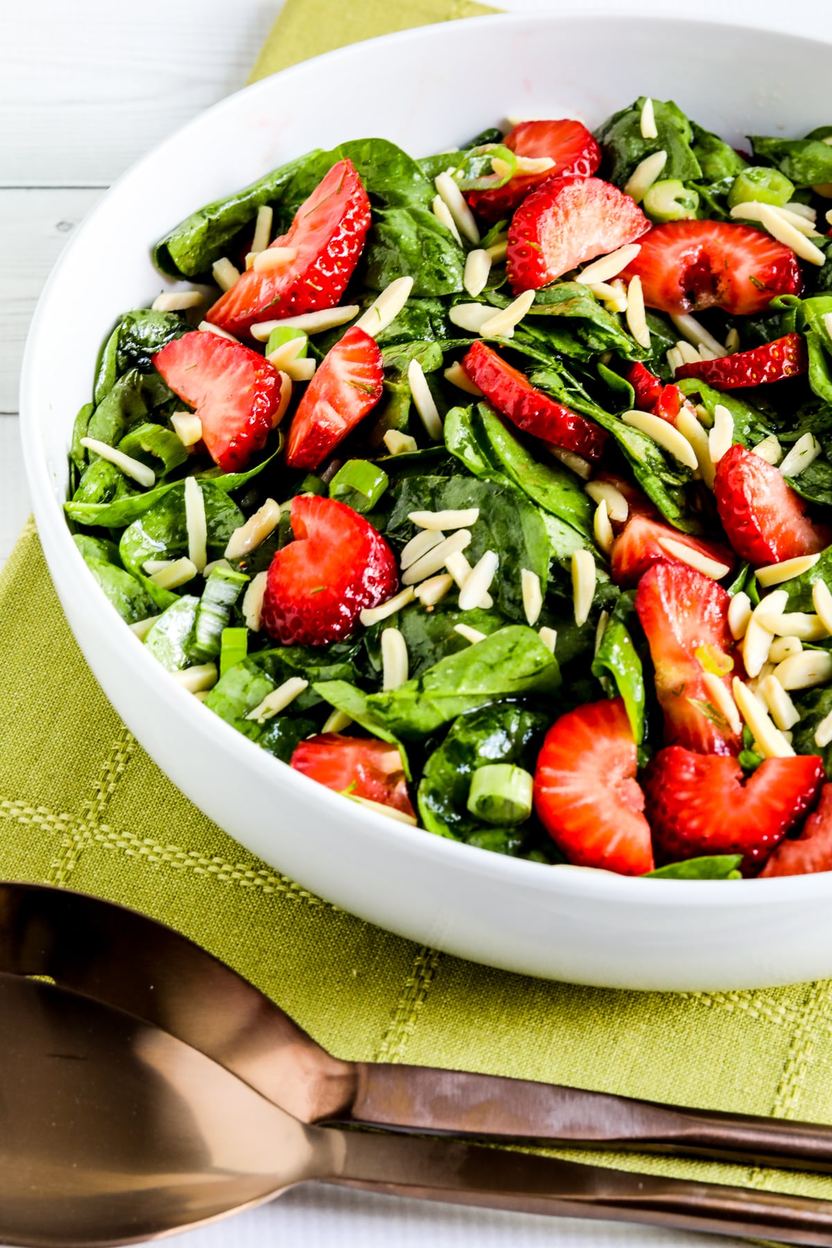 Strawberry and spinach salad shown in a serving bowl.