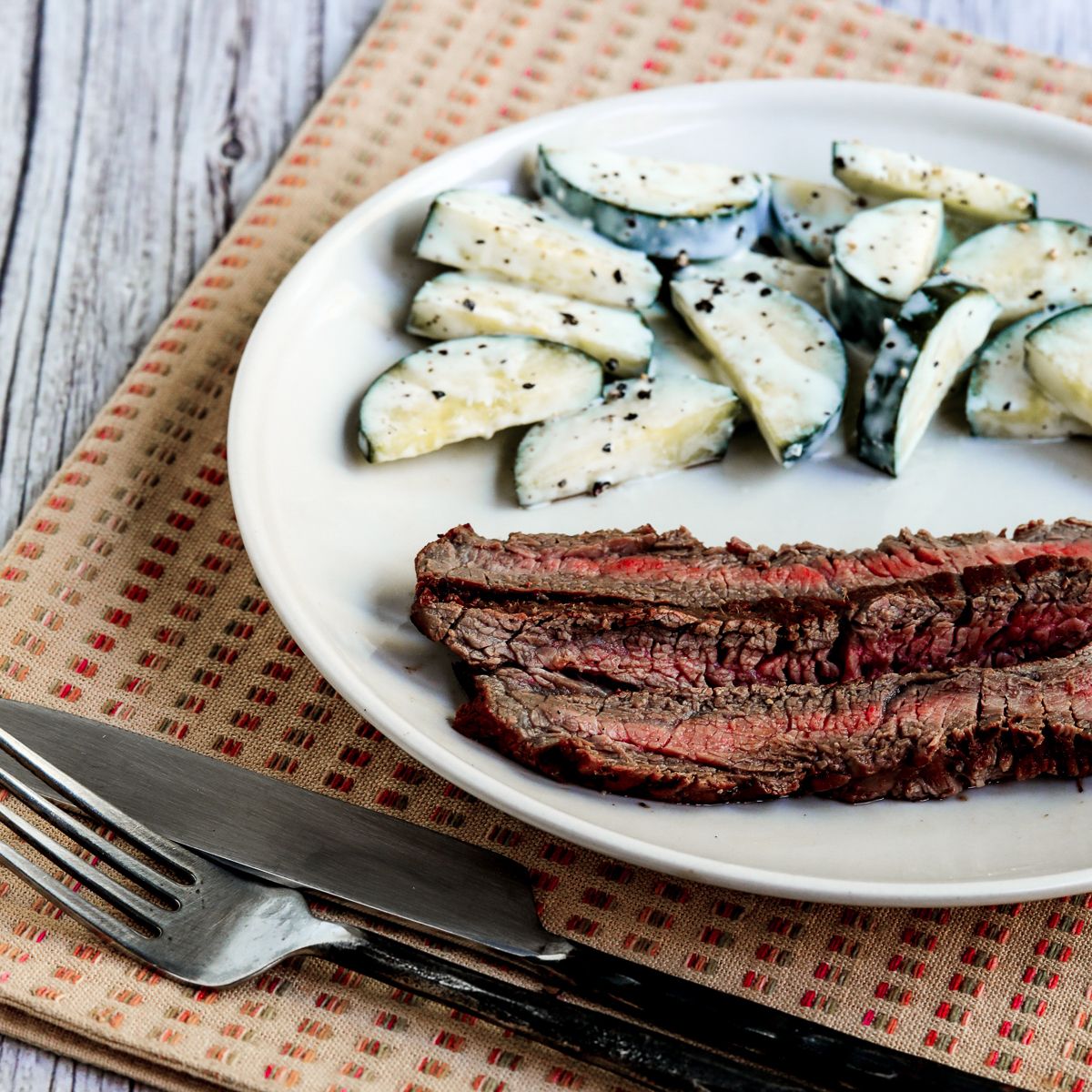 Square image of Marinated Grilled Flank Steak on serving plate.