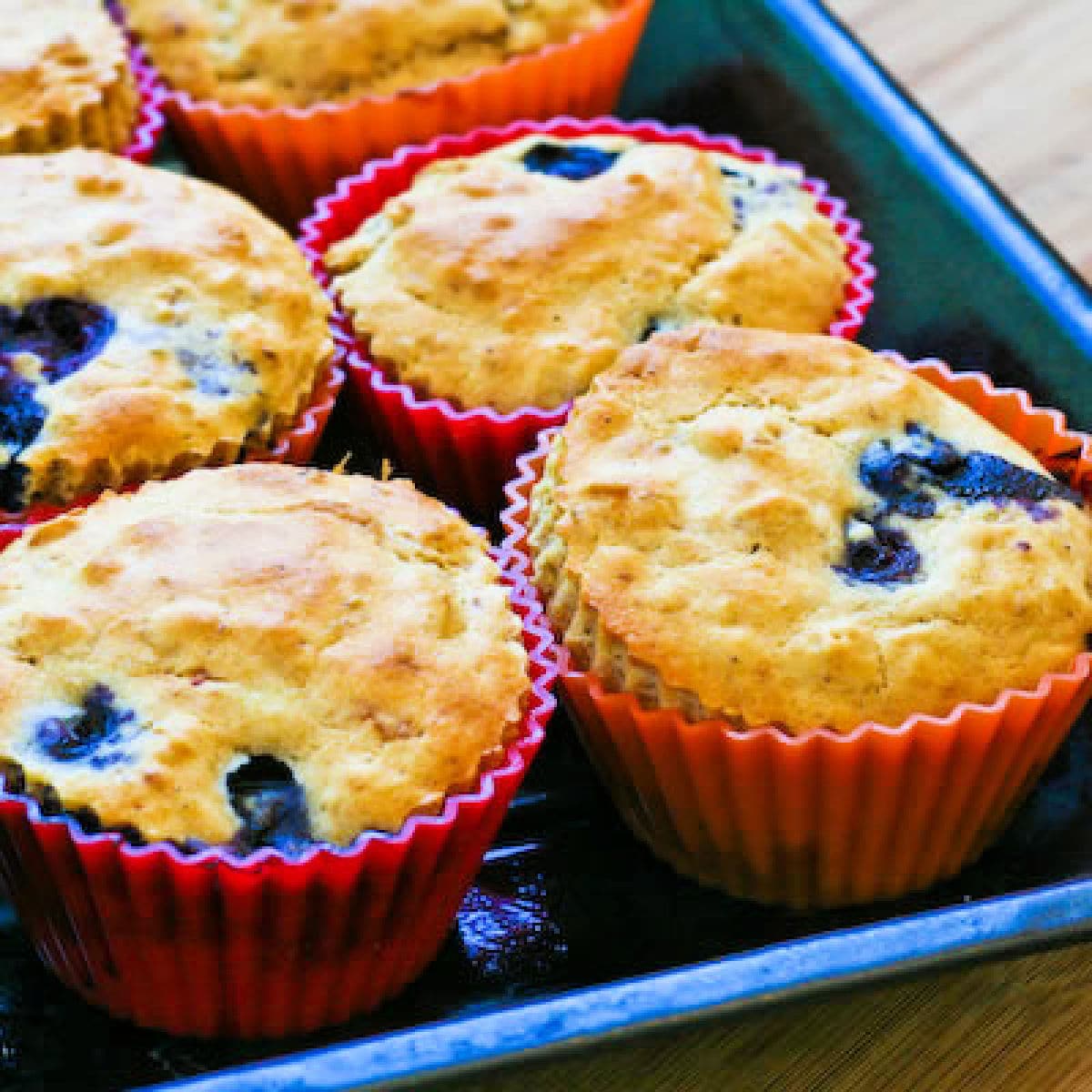 Low-Sugar Blueberry Muffins shown in muffin baking cups on baking sheet.