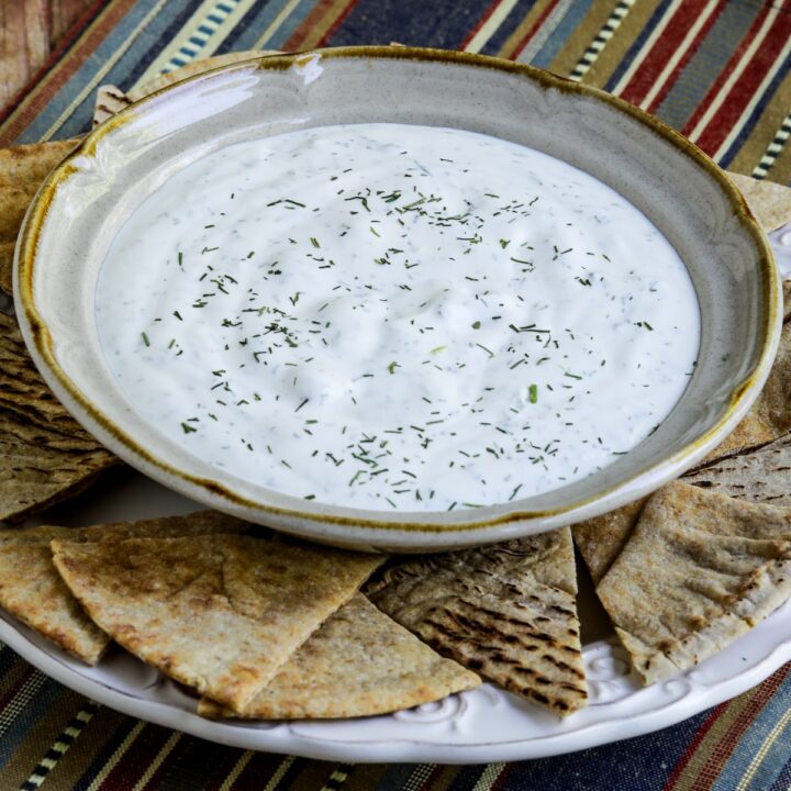 Tzatziki Sauce shown in bowl on plate with pita bread.