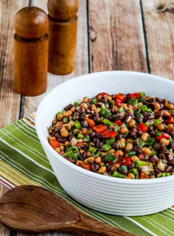 Black Bean Salad with Black-Eyed Peas shown in serving bowl with serving spoon and salt-pepper shakers