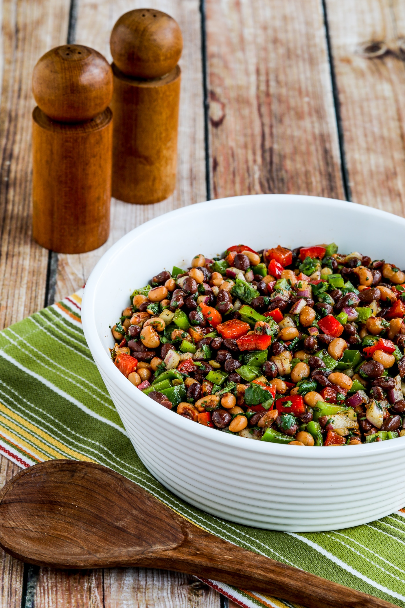 Black Bean Salad with Black-Eyed Peas shown in serving bowl with serving spoon and salt-pepper shakers