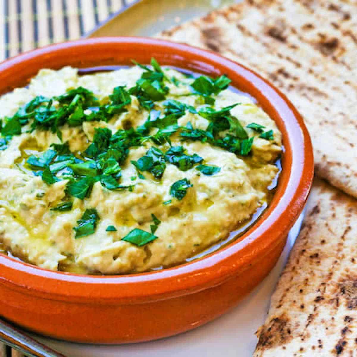 Julia Child's White Bean Hummus in terra cotta bowl with low-carb pita on the side.