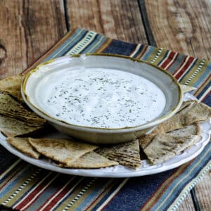 Square image for Tzatziki Sauce shown in bowl on plate with pita bread.