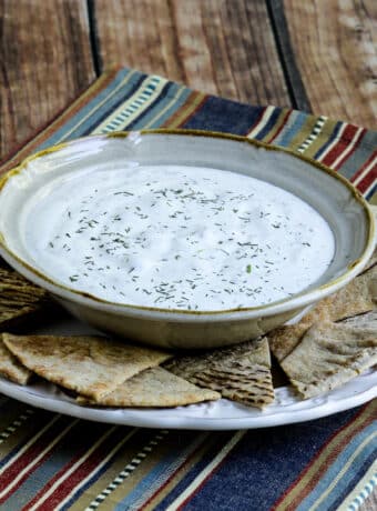 Square image for Tzatziki Sauce shown in bowl on plate with pita bread.