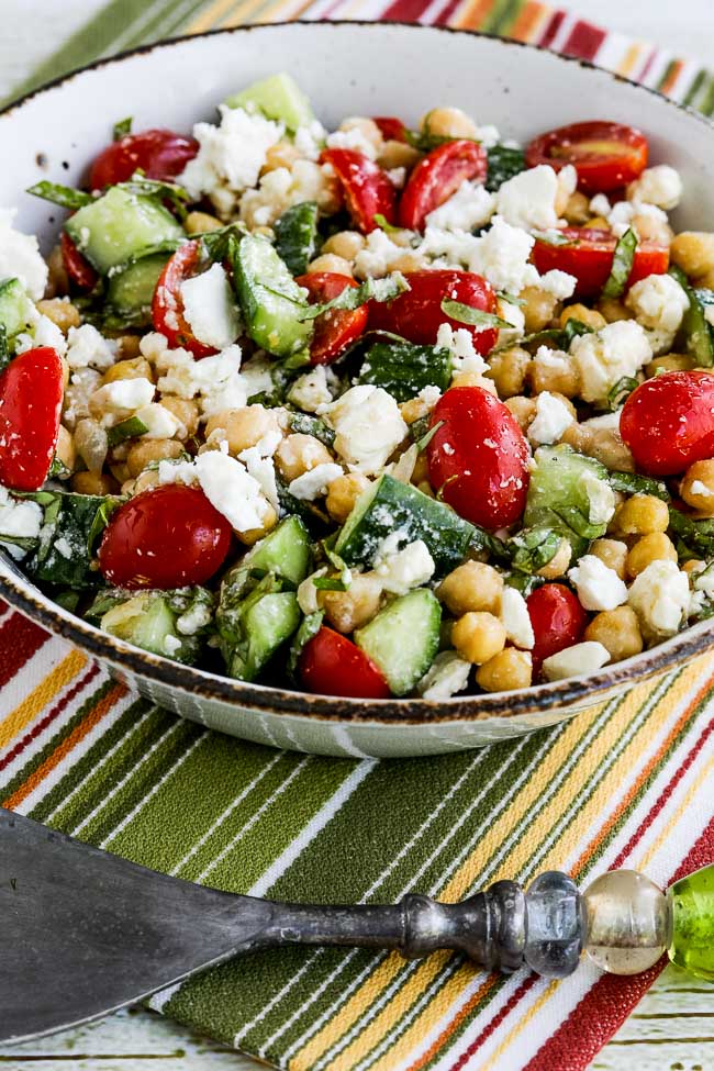 Tomato Cucumber Chickpea Salad shown in bowl on striped napkin.