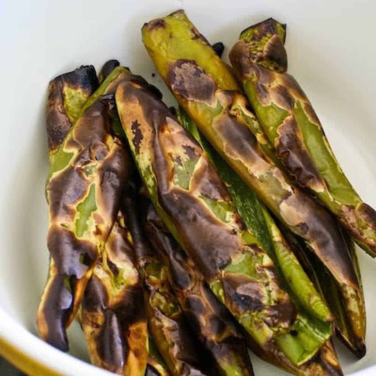 roasted green chiles with charred skin shown in bowl 
