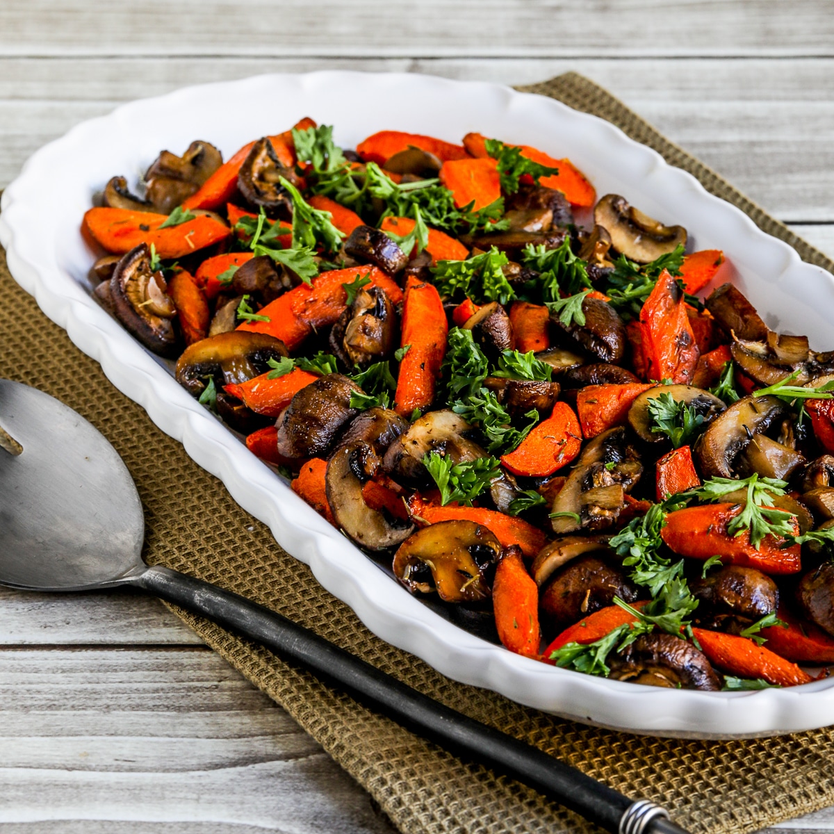 Roasted carrots and mushrooms on a serving plate with a fork