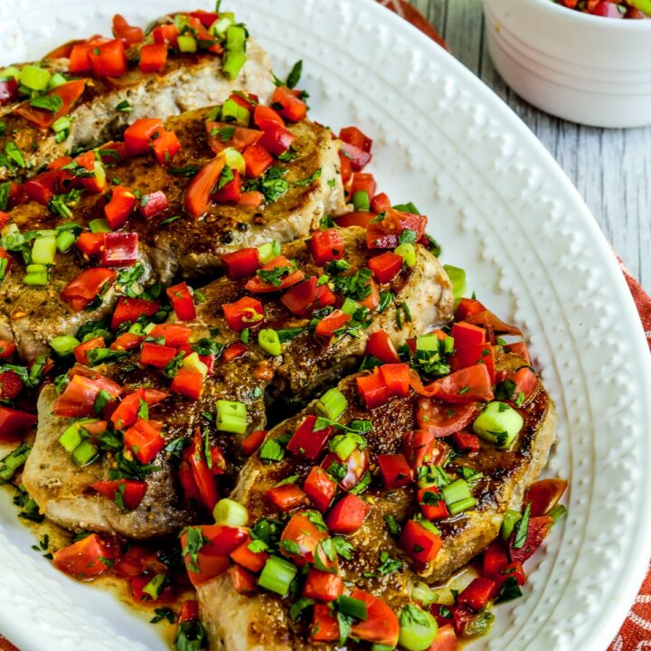 Creole Pork Chops with Tomato-Pepper Relish shown on serving plate with extra relish in bowl.