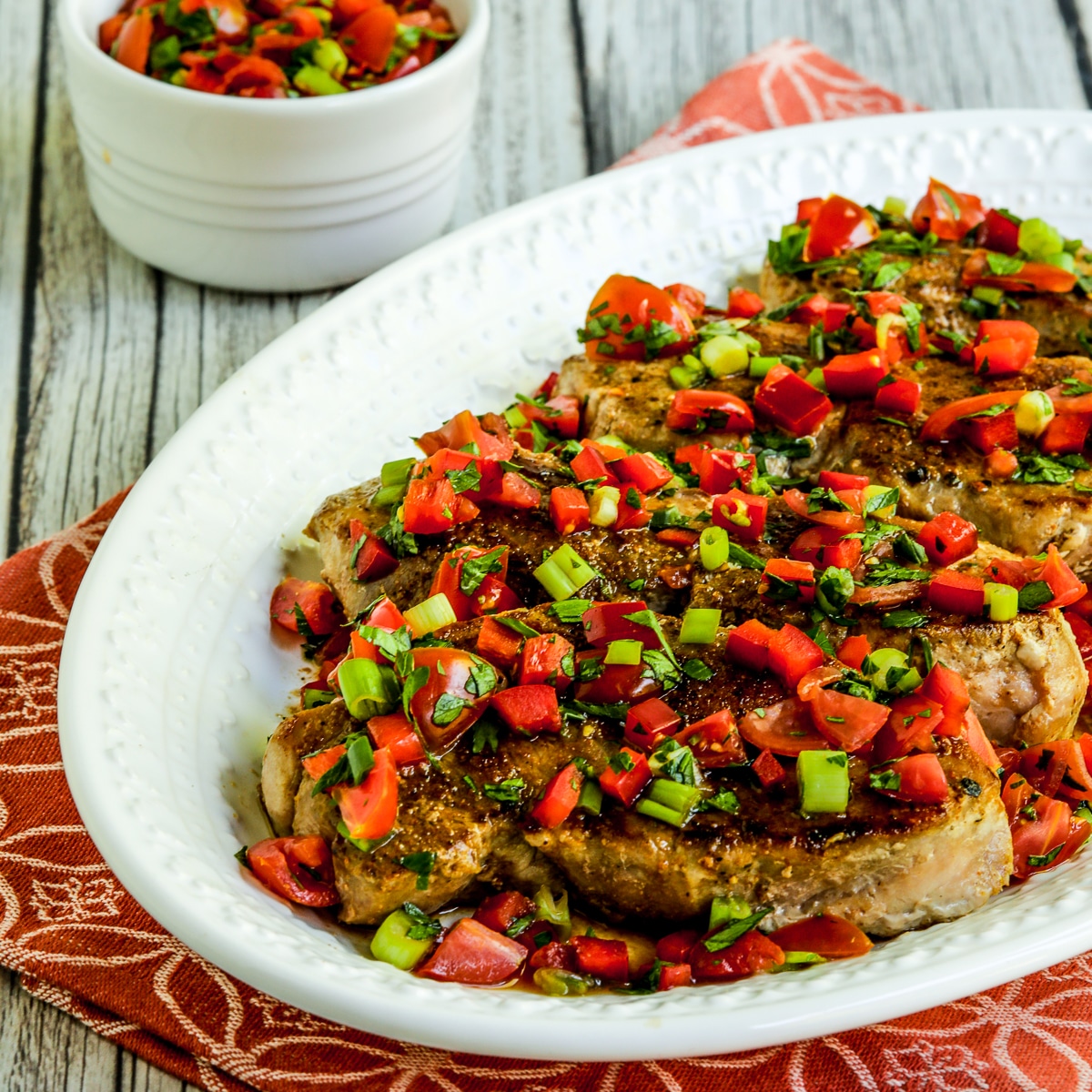 Square image of creole pork chops with tomato pepper relish.