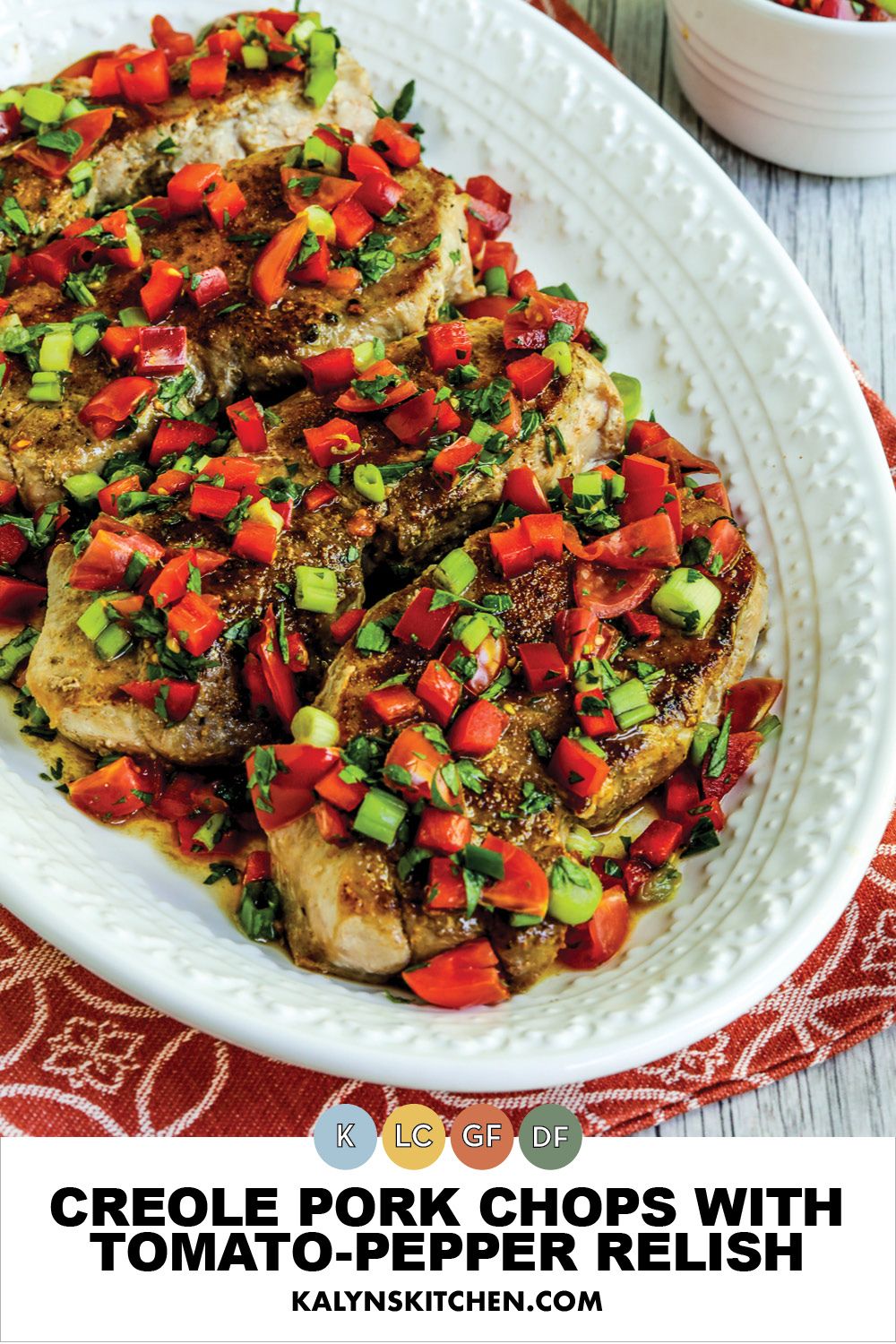 A Pinterest image of a Creole pork chop with tomato and pepper relish, with pork on a serving plate.