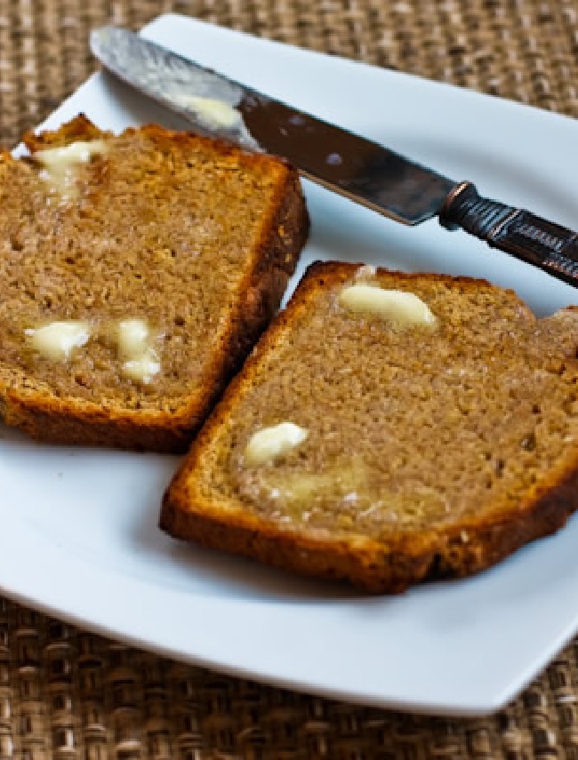 Brown Irish soda bread laid out on a serving plate with a knife and melted butter