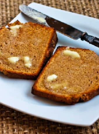 Square image of Brown Irish Soda Bread on plate with knife and butter.