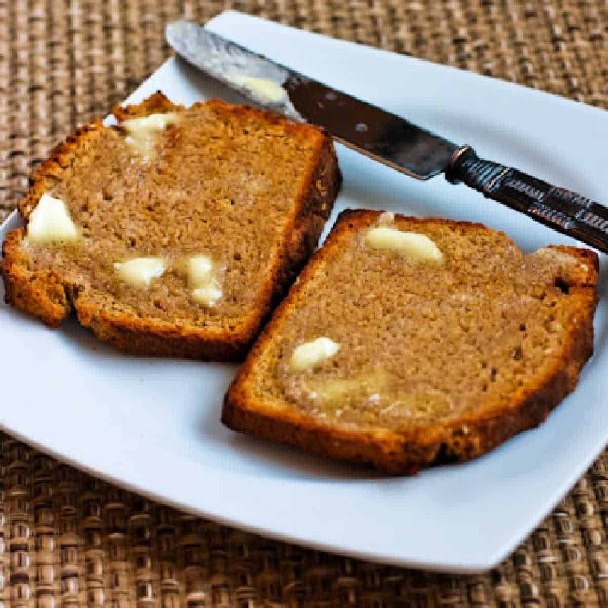 Square image of Brown Irish Soda Bread on plate with knife and butter.