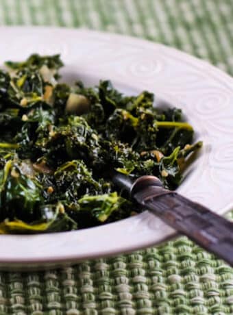 Square image for Sauteed Kale with Garlic and Onion shown in serving bowl with spoon.