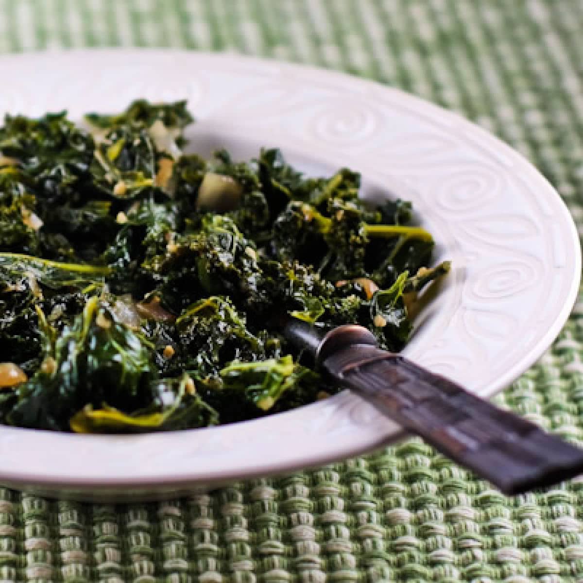 Square image for Sauteed Kale with Garlic and Onion shown in serving bowl with spoon.