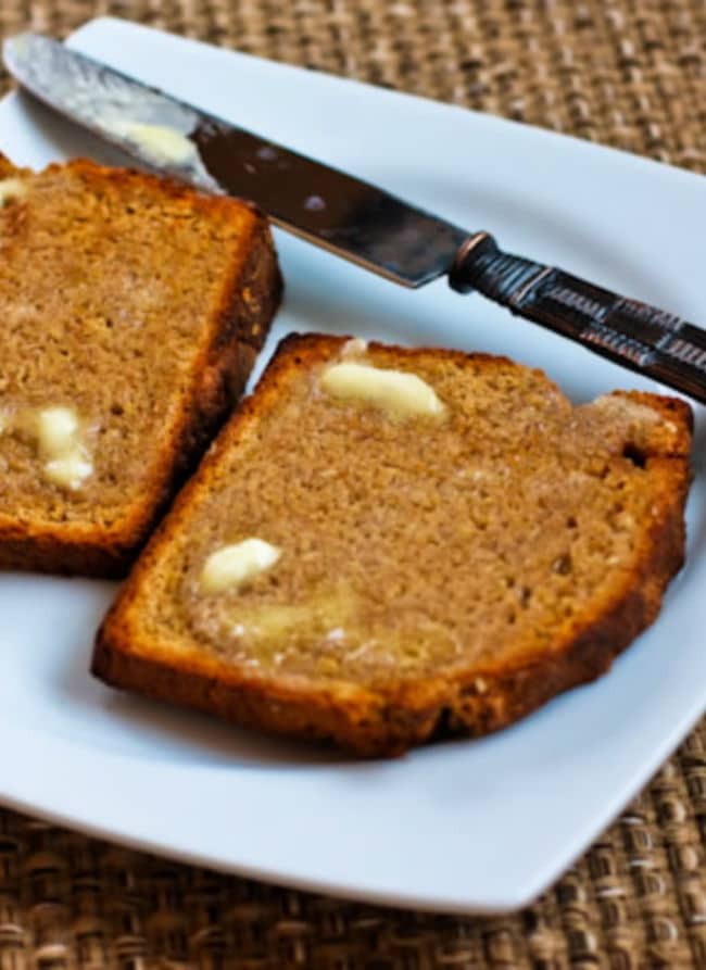 Brown Irish soda bread shown on a plate with butter and a knife.