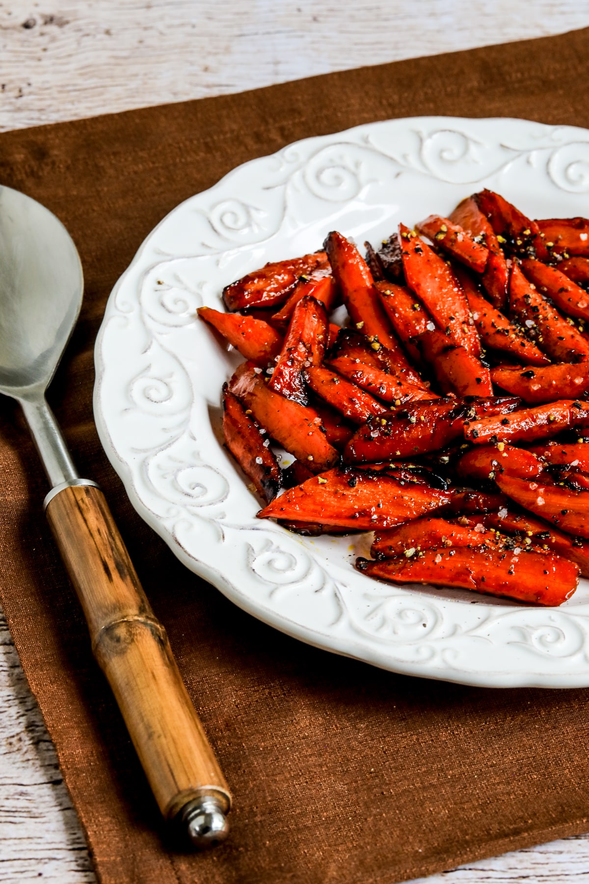 Maple Glazed Carrots on serving platter with napkin and serving spoon.
