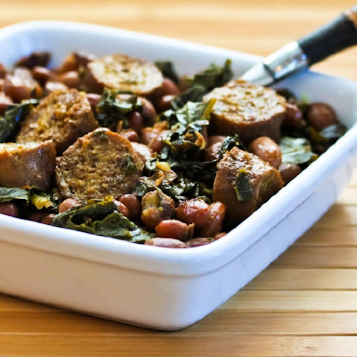 Greens and Beans with Sausage shown in square serving bowl.