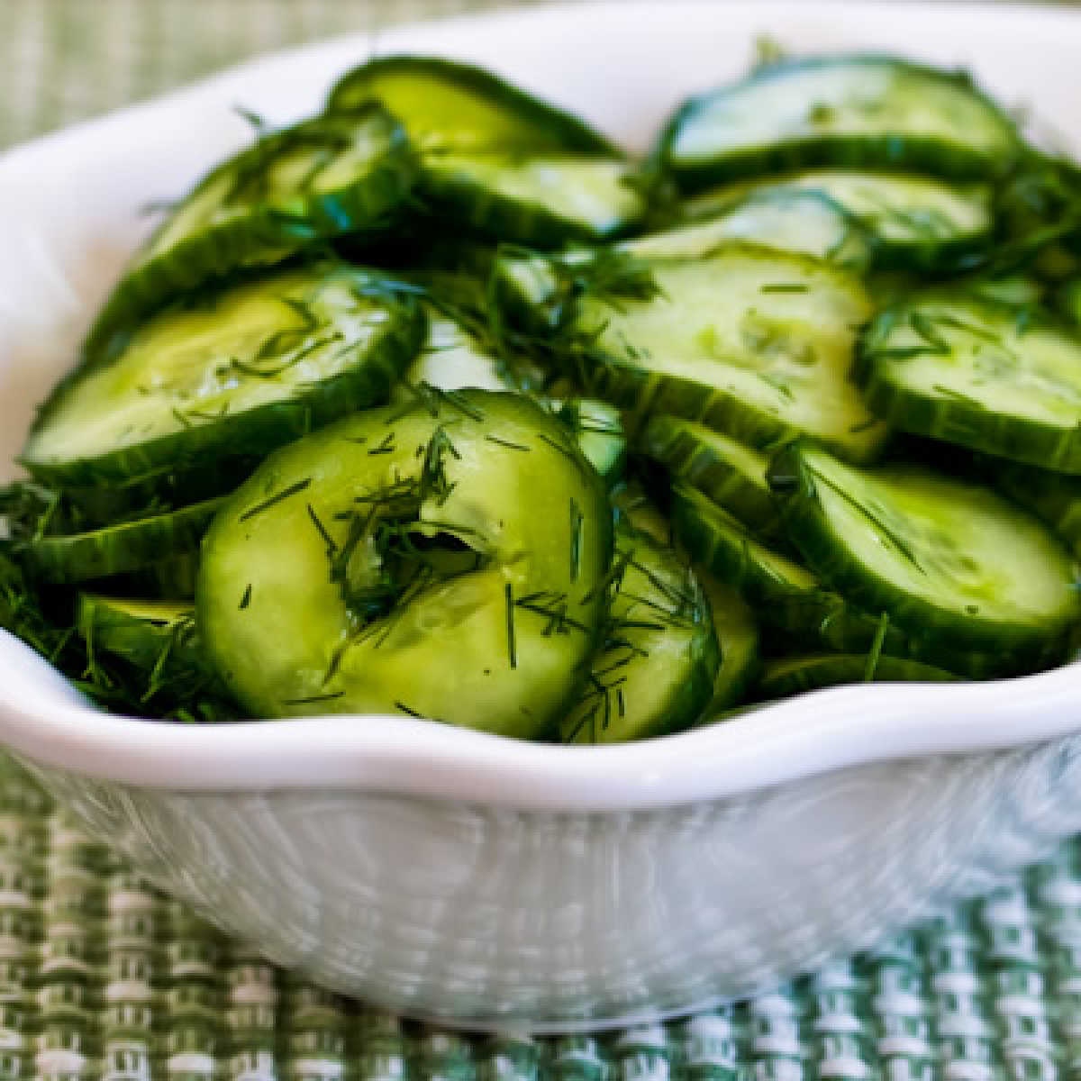 Sweet and sour cucumber salad shown in a serving bowl with dill