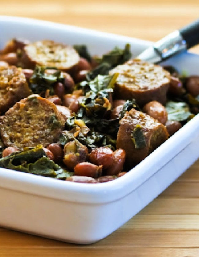 Greens and Beans with Sausage in serving dish, cropped image.