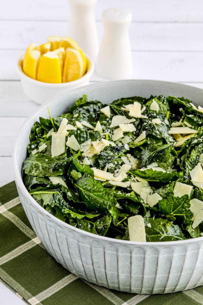 Lemon Parmesan Kale Salad in serving bowl with lemons in background