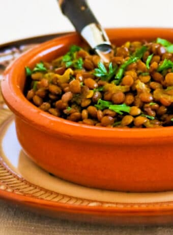 Curried Lentils shown in terra cotta serving dish with spoon.