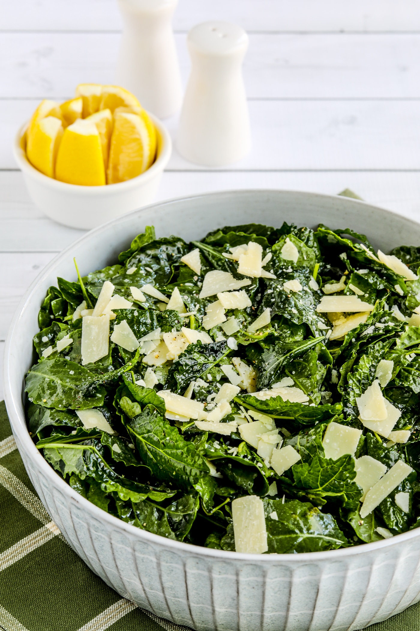 close-up photo of Lemon Parmesan Kale Salad in serving dish with lemons in background