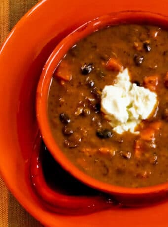 Square image for Black Bean Sweet Potato Soup in orange bowl with sour cream on top.