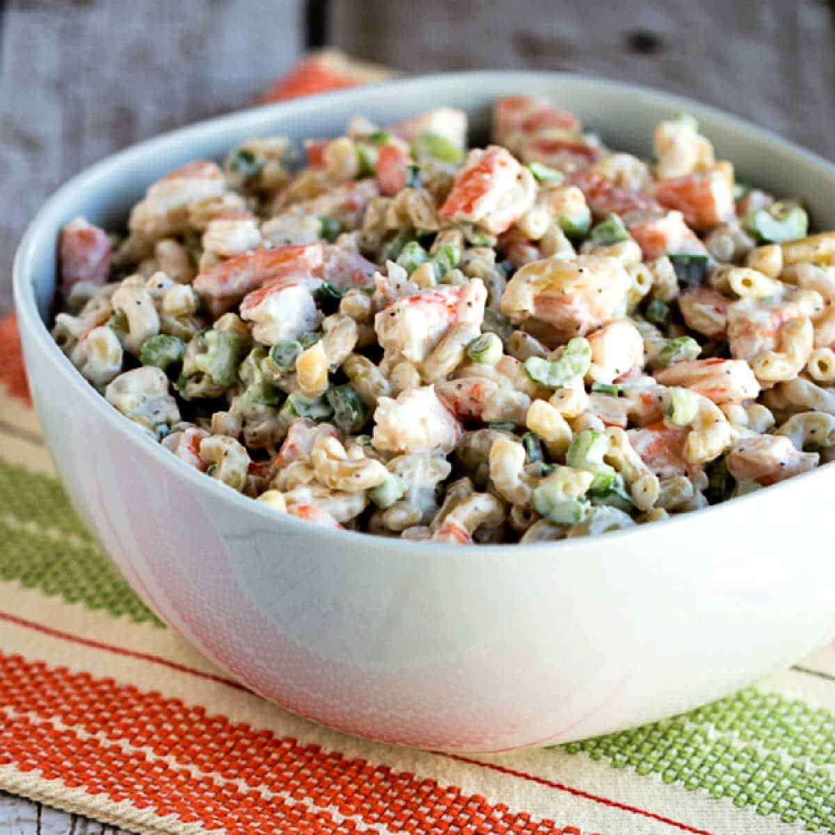 A square image of a family favorite shrimp and macaroni salad is displayed in a napkin serving bowl.