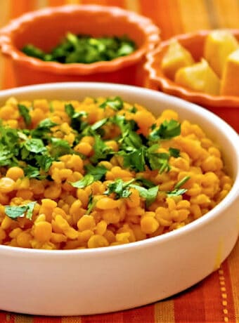Square image of Lemony Yellow Split Pea Recipe in serving bowl with lemons and cilantro.