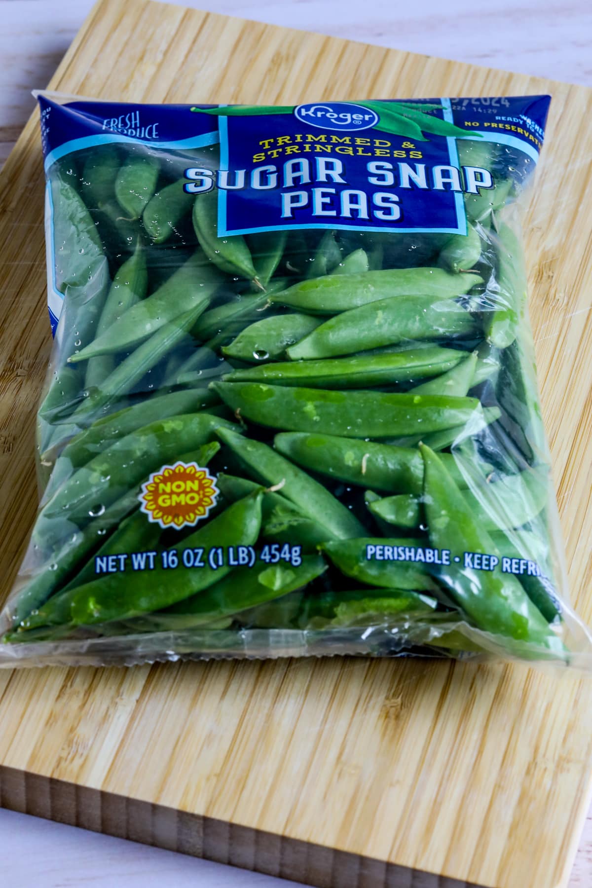 Sugar Snap Peas in bag, shown on cutting board.