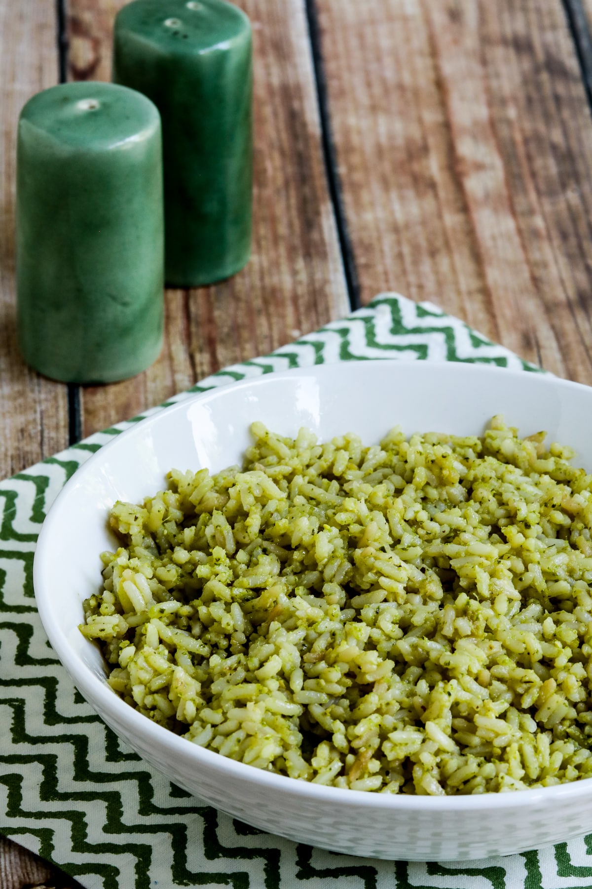 Lemon Pesto Rice Recipe in serving bowl with spoon and green salt-pepper shakers.