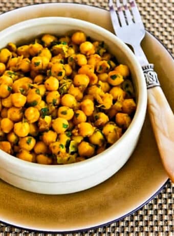 Square image for Curried Chickpea Salad shown in bowl with plate and fork.