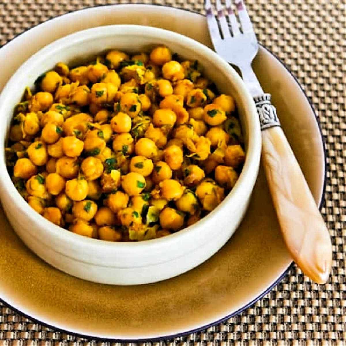 Square image for Curried Chickpea Salad shown in bowl with plate and fork.