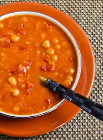 Square image for Red Lentil and Chickpea Soup shown in bowl on orange plate.