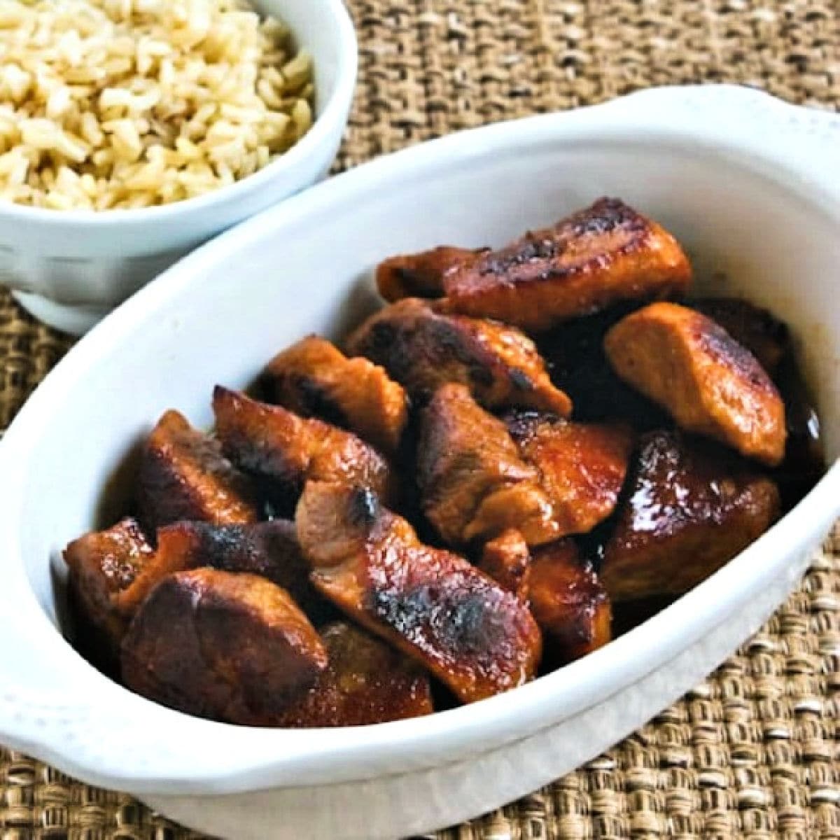 Square image of Filipino Pork Adobo in serving dish with rice.
