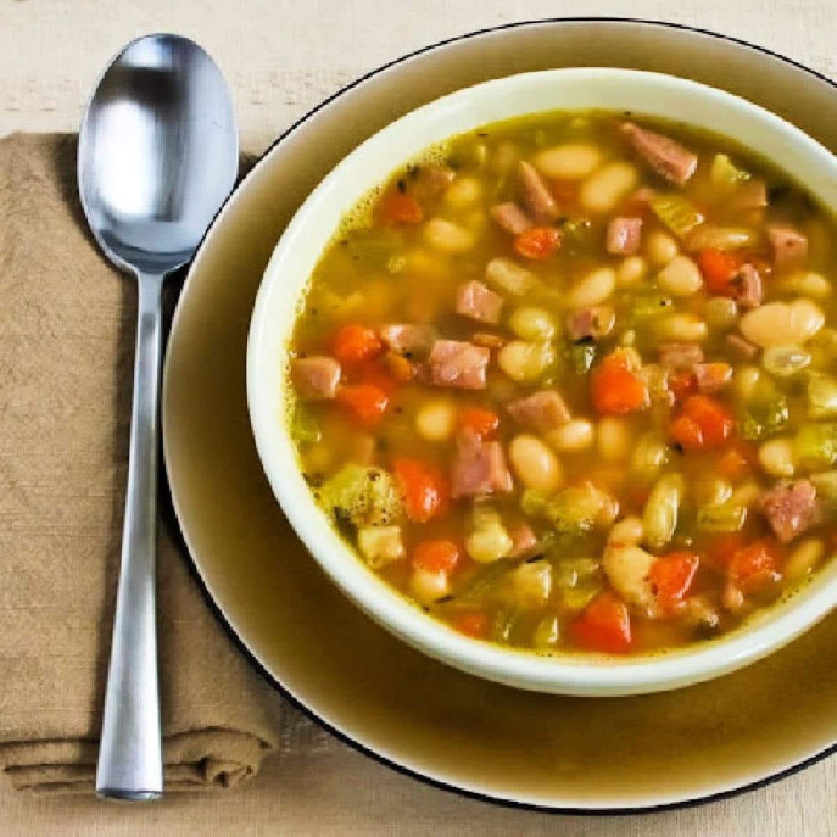 Square image of White Bean Soup with Ham shown in bowl with spoon.