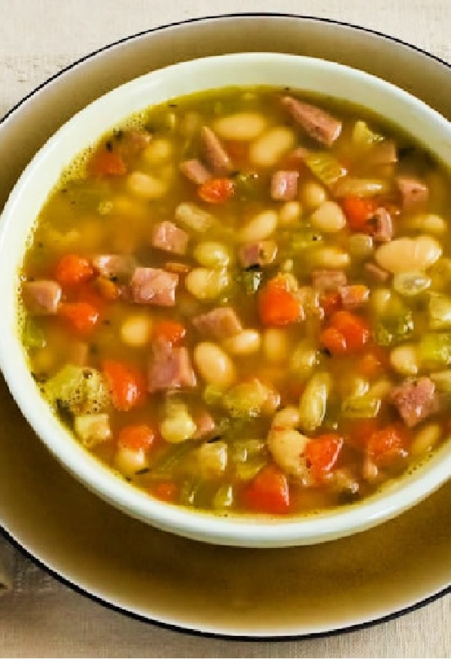 White Bean Soup with Ham shown in bowl with plate underneath.