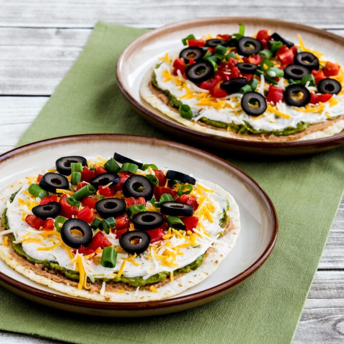 Square image of Seven Layer Dip Tostadas shown on two serving plates
