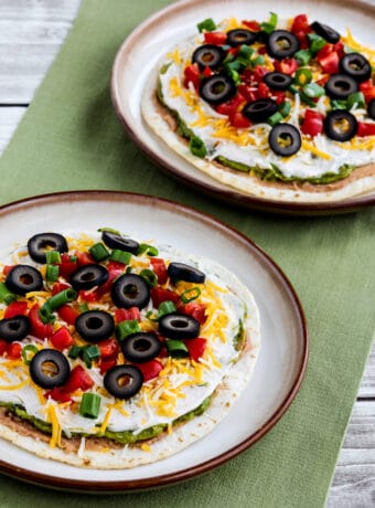 Seven Layer Dip Tostadas shown on two serving plates with green napkin